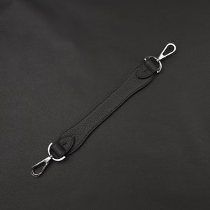 May include: A black leather strap with silver metal clasps. The strap is about 15 inches long.