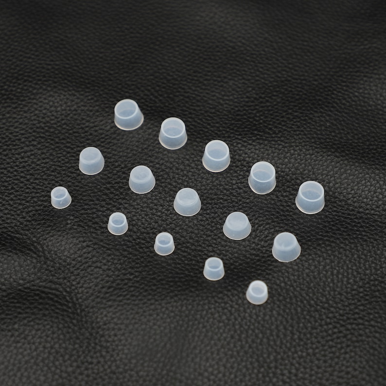 May include: Assortment of clear silicone bottle stoppers in various sizes. The stoppers are arranged on a black surface.