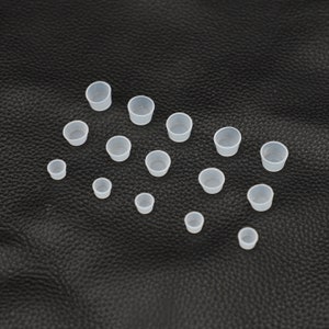 May include: A set of 16 white plastic cups of varying sizes. The cups are arranged on a black surface.