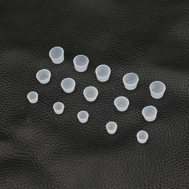 May include: A set of 16 white plastic cups of varying sizes. The cups are arranged on a black surface.