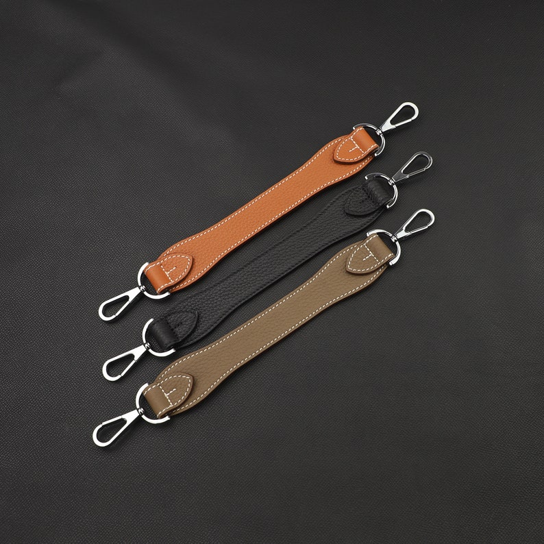 May include: Three leather straps with silver metal clasps. The straps are brown, black, and tan.