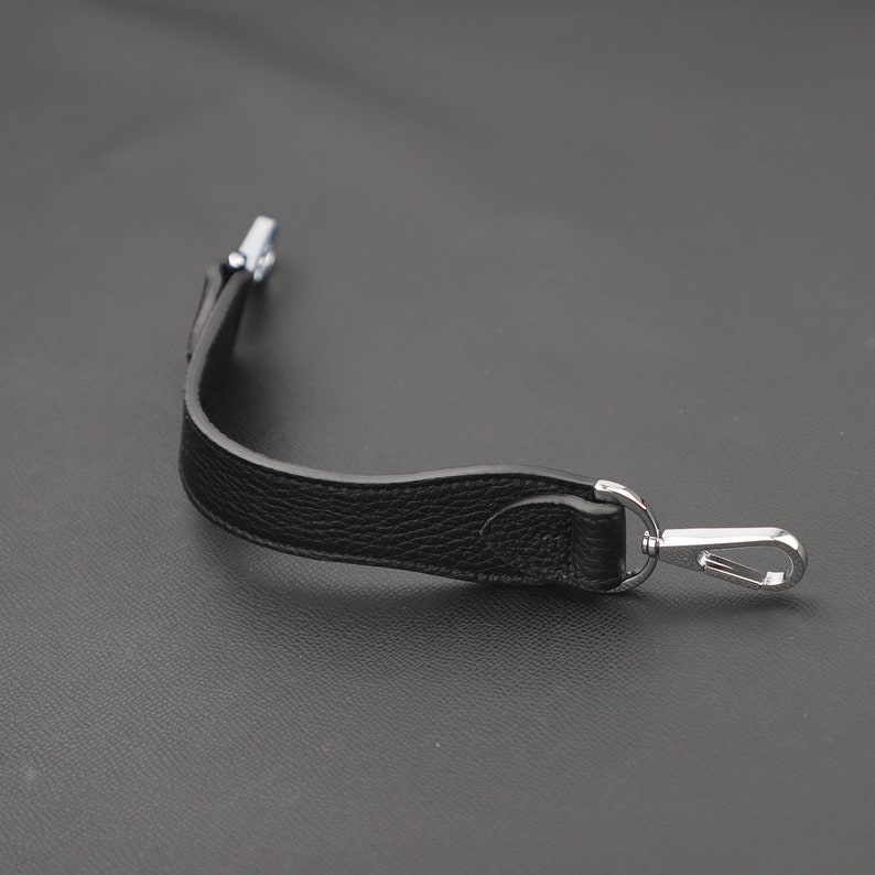 May include: Black leather strap with a silver hook and loop closure.