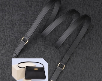 May include: Black leather shoulder strap with gold hardware. The strap is shown coiled on a black surface and attached to a black handbag.