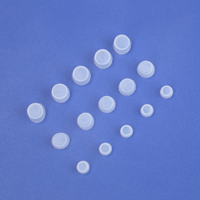May include: Assortment of white rubber caps of various sizes on a blue background.