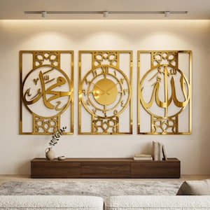 Op de afbeelding: Een set van drie rechthoekige, goudkleurige wandpanelen met ingewikkelde geometrische patronen. Het linkerpaneel toont Arabische kalligrafie, het middelste paneel bevat een ronde analoge klok met Arabische cijfers en het rechterpaneel toont extra Arabische kalligrafie.