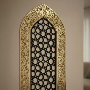 Peut inclure: Panneau mural décoratif en forme d'arche, avec un cadre doré et un treillis géométrique noir. Le cadre est orné d'une calligraphie arabe complexe. Le panneau est fixé sur un mur de couleur neutre.