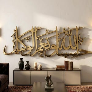 Könnte beinhalten: Ein großes Wandkunstobjekt aus goldfarbenem Metall mit komplexer arabischer Kalligrafie. Die Schrift ist poliert und reflektierend und horizontal an einer schlichten Wand montiert. Das Design besteht aus fließenden, miteinander verbundenen Zeichen, die ein zusammenhängendes, dekoratives Statement-Stück mit metallischem Finish bilden.