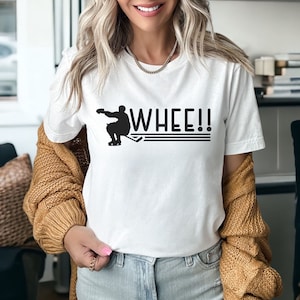 K&ouml;nnte beinhalten: Wei&szlig;es T-Shirt mit einer schwarzen Silhouette eines Hockeyspielers und dem Text "WHEE!!" auf der Vorderseite.