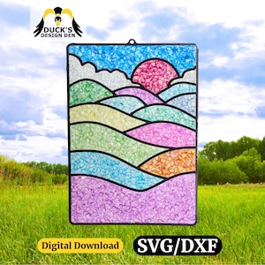 Peut inclure: Un panneau rectangulaire en vitrail représentant un paysage avec un soleil rose, un ciel bleu et des collines ondulantes dans des tons de vert, de violet et d'orange. Le panneau est encadré en noir et contient le texte "Digital Download" et "SVG/DXF".