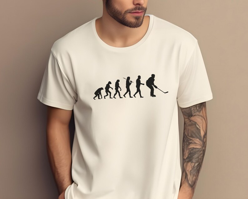 K&ouml;nnte beinhalten: Wei&szlig;es T-Shirt mit einer schwarzen Grafik der Evolution des Menschen, die mit einem Hockeyspieler endet, der einen Schl&auml;ger h&auml;lt.
