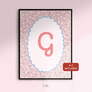 Pode incluir: Impressão emoldurada com a letra "G" em rosa, sobre um oval branco com borda azul recortada. O fundo é um padrão floral rosa. O texto "A-Z INCLUDED" está num retângulo vermelho.
