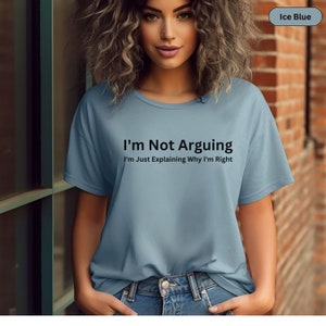 May include: Ice blue t-shirt with the text "I'm Not Arguing, I'm Just Explaining Why I'm Right" in black. The shirt is a crew neck style and is made of a soft material. The model is wearing blue jeans.