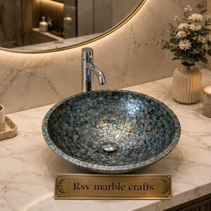 May include: A mosaic-tiled, round bathroom sink with a silver faucet is the focal point of this image. A lit candle, soap dispenser, and a small vase with flowers are also visible. The sink is labeled "Rsv marble crafts".