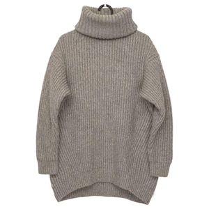 May include: A light gray, ribbed knit turtleneck sweater. The sweater has a loose, oversized fit with long sleeves and a high, folded turtleneck collar. The fabric appears to be a soft, warm material, perfect for cooler weather. The sweater is hanging on a black hanger.