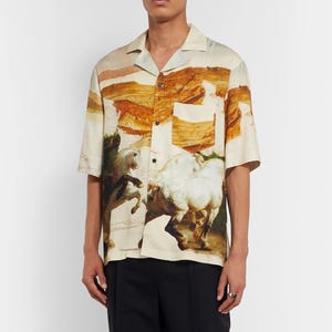 May include: Short-sleeved button-down shirt with a landscape and horse painting design. The shirt features a classic collar, a chest pocket, and a beige, brown, and green color palette. The artwork depicts white horses in a dynamic pose.