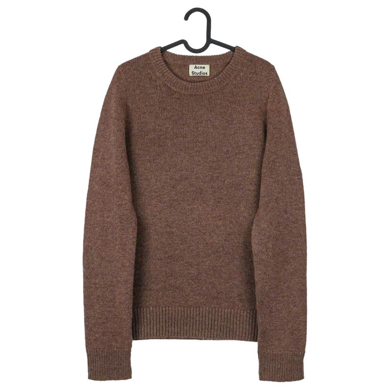 Peut inclure: Un pull marron &agrave; col rond et manches longues, suspendu &agrave; un cintre noir. Le pull a un ourlet et des poignets c&ocirc;tel&eacute;s. L'&eacute;tiquette sur le pull indique "Acne Studios".