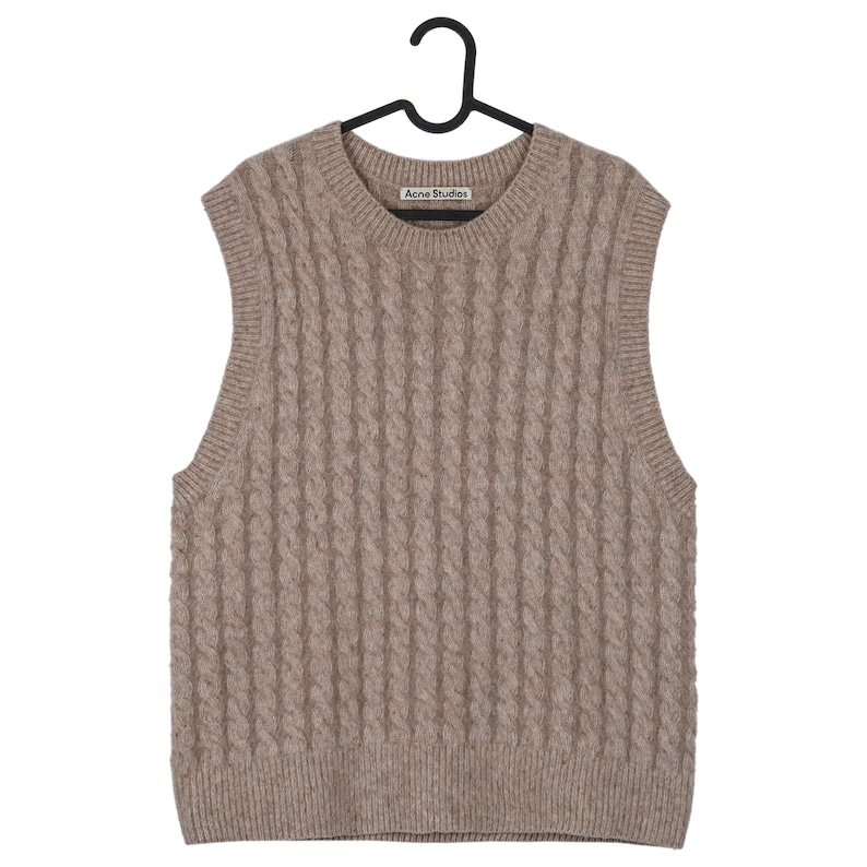 May include: A tan cable-knit sweater vest with a crew neck, hanging on a black hanger. The vest has a textured pattern and the brand name "Acne Studios" is visible on the neckline.