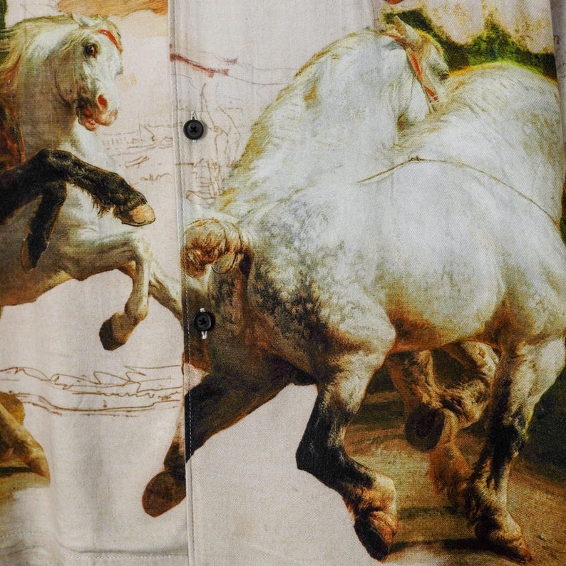 May include: Button-down shirt featuring a detailed print of white horses in a classical painting style. The horses are depicted in dynamic poses, with visible brushstrokes and a vintage aesthetic. The shirt has black buttons.