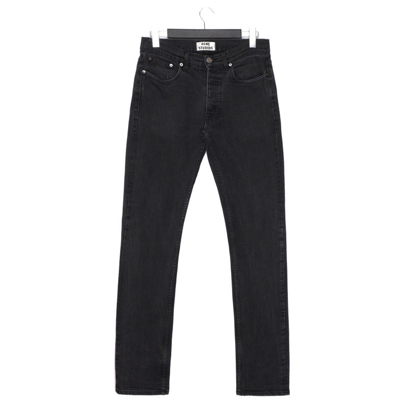 Pu&ograve; includere: Un paio di jeans neri in denim appesi a una gruccia nera. I jeans hanno una chiusura con bottoni e cinque tasche. Il nome del marchio "ACNE STUDIOS" &egrave; visibile sull'etichetta. I jeans sono a gamba dritta.