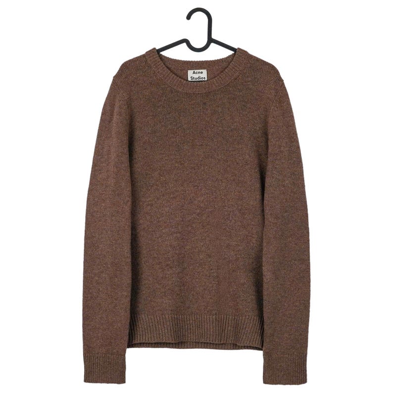 May include: A brown crew neck sweater hanging on a black hanger. The sweater has a ribbed hem and cuffs. The label "Acne Studios" is visible on the neckline. The sweater is made of a soft, textured material.
