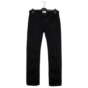 May include: Black denim jeans hanging on a black hanger. The jeans have a classic five-pocket design and a straight leg fit. The brand label "Acne Studios" is visible on the hanger.
