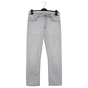 May include: Light gray denim jeans hanging on a black hanger. The jeans have a classic five-pocket design with a button and zipper closure. The denim appears to be a medium weight, suitable for various seasons.