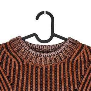 May include: Close-up of a brown and orange knit sweater on a black hanger. The sweater has a ribbed pattern with vertical stripes. The neckline is a lighter shade of brown.