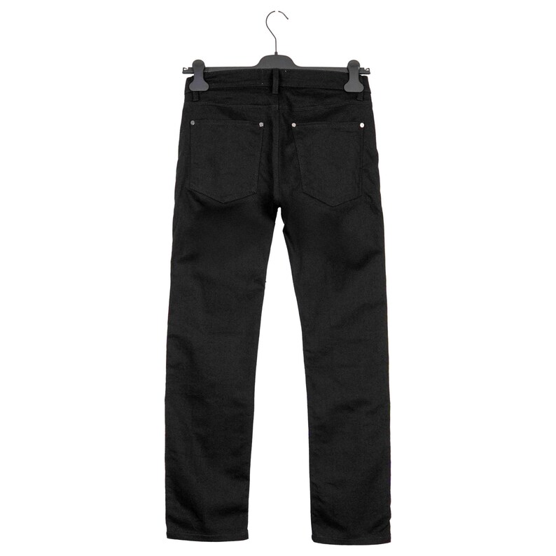May include: Back view of black denim jeans hanging on a black hanger. The jeans have two back pockets and silver rivets. The pants are straight-legged and appear to be made of a sturdy material.
