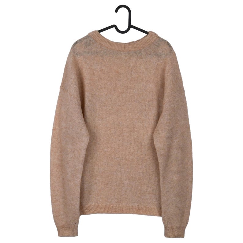 Pu&ograve; includere: Un maglione beige con scollo tondo e maniche lunghe &egrave; appeso a una gruccia nera. Il maglione ha una consistenza morbida e soffice e una vestibilit&agrave; rilassata, adatta all'abbigliamento casual. Il colore neutro lo rende versatile.