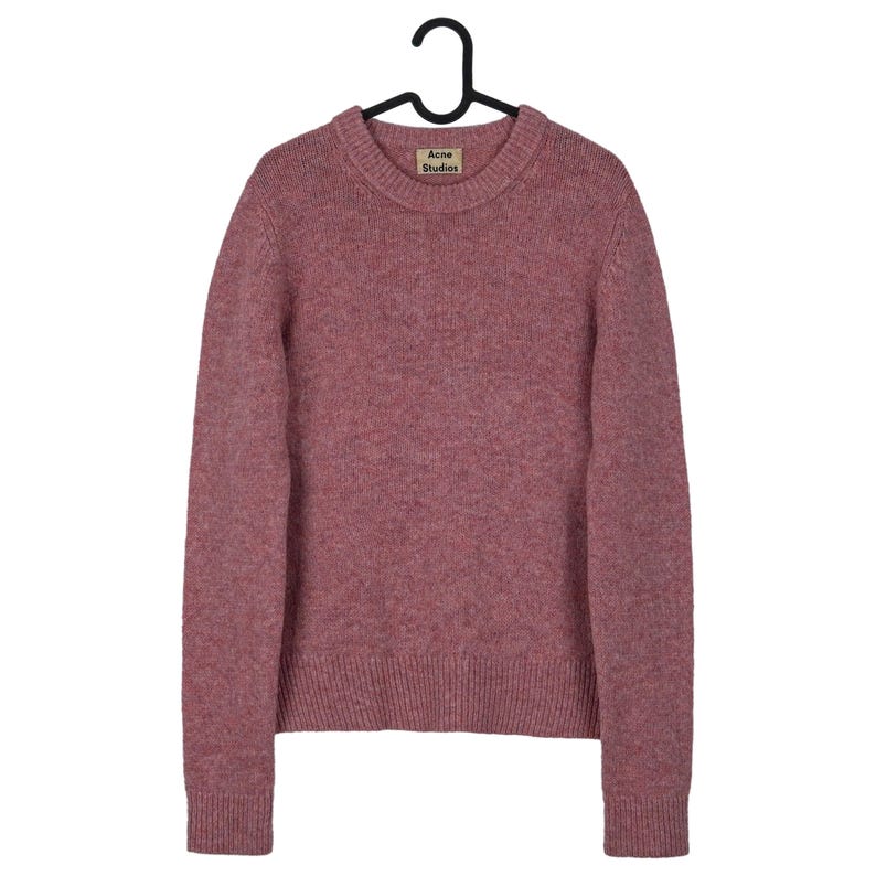 May include: A dusty rose crew neck sweater with long sleeves, hanging on a black hanger. The sweater has a ribbed hem and cuffs. A small tag with the text "Acne Studios" is visible near the neckline.