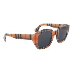 May include: Angled sunglasses with a tan, red, and black plaid pattern. The sunglasses have dark gray lenses and a unique, geometric frame shape. The arms of the sunglasses also feature the plaid design.