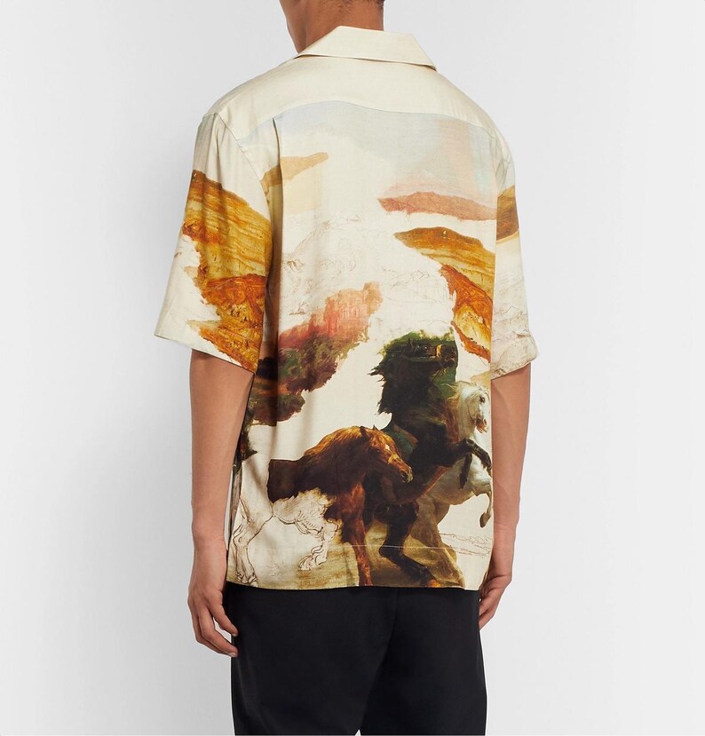 May include: Short-sleeved button-up shirt with a landscape and horse painting design. The shirt features a cream-colored base with a colorful print of horses and a mountainous landscape.
