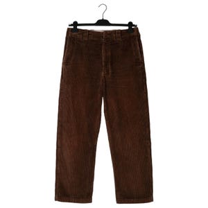May include: Brown corduroy pants hanging on a black hanger. The pants have a classic, straight-leg design with a button and zipper closure. The corduroy fabric has a ribbed texture and a rich, warm brown color.