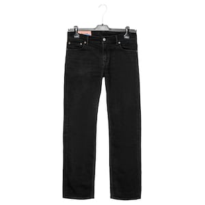 May include: Black denim jeans hanging on a black hanger. The jeans have a classic five-pocket design with a button and zip closure. The jeans are a solid black colour and appear to be made of a durable denim material.
