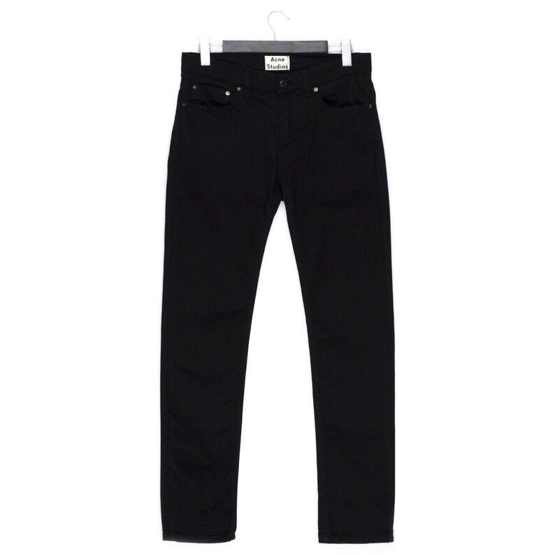 May include: Black denim jeans hanging on a hanger. The jeans have a classic five-pocket design and a straight leg fit. The brand label "Acne Studios" is visible on the back pocket. The jeans are made of a sturdy, dark-colored denim.