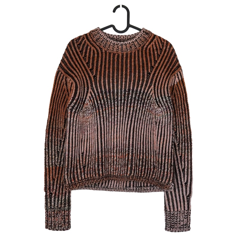 May include: A brown and black striped sweater with a ribbed texture, hanging on a black hanger. The sweater has a crew neck and long sleeves. The color palette includes shades of brown, black, and a hint of pink.