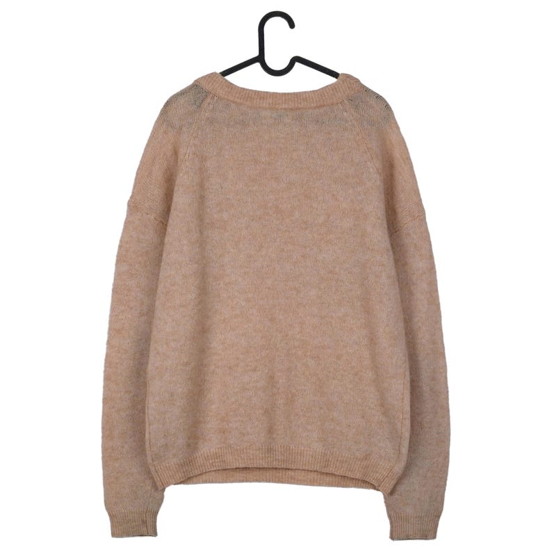 Pu&ograve; includere: Un maglione color beige &egrave; appeso a una gruccia nera. Il maglione ha uno scollo tondo e maniche lunghe. Il materiale appare morbido e soffice. L'indumento &egrave; di un colore neutro, adatto a vari outfit.