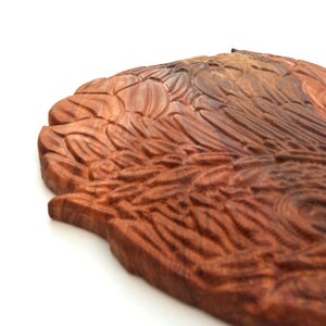 May include: A wooden carving of a bird's wing, featuring intricate details and a rich brown colour.
