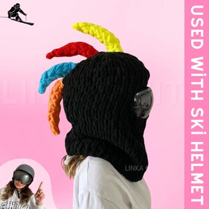 May include: Black crochet ski mask with colorful yarn accents and a black visor. The text "LINKA" is visible on the mask.