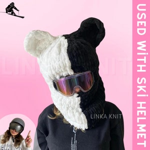 May include: Black and white knit ski mask with ear flaps and a pair of goggles. The mask is half black and half white, with a black knit on the left side and a white knit on the right side. The text "LINKA KNIT" is visible on the bottom right side of the mask. The text "USED WITH SKI HELMET" is visible on the right side of the image.
