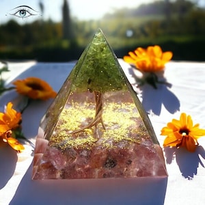 May include: A clear pyramid with a green crystal tree inside. The base of the pyramid is filled with pink and purple crystals and gold glitter.