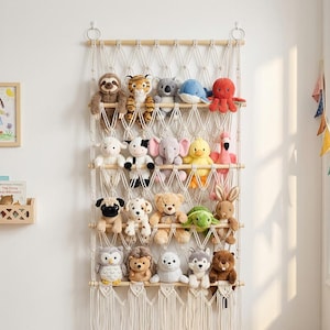 Op de afbeelding: Een macramé wandorganizer met vier horizontale houten staven en een net van gevlochten katoenen koord. De organizer bevat twintig verschillende pluche dieren, waaronder een luiaard, tijger, koala, walvis, octopus, schaap, koe, olifant, eend, flamingo, mopshond, hond, beer, schildpad, konijn, uil, egel, zeehond, wolf en bever.