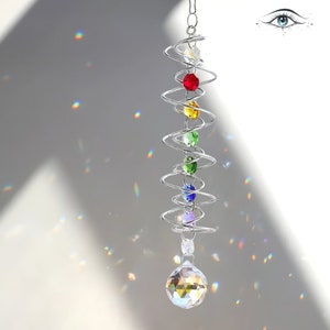 Könnte beinhalten: Ein Kristall-Sonnenfänger mit einem Spiraldesign und einem Regenbogen aus Farben. Der Sonnenfänger hat eine klare Kristallkugel am Boden.