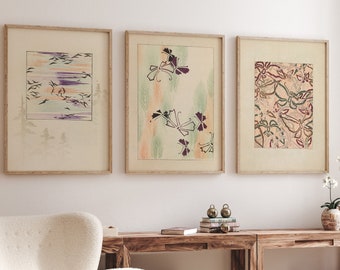 May include: Three framed prints with floral and butterfly designs hang on a white wall above a wooden table with a white armchair and a small wooden table with a book on top.