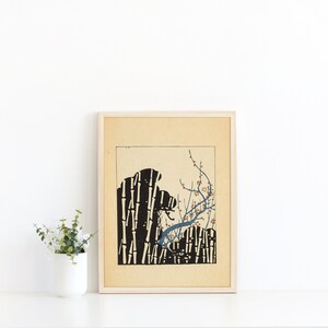 Pode incluir: Uma impressão emoldurada de uma ilustração em preto e branco de uma floresta de bambu com um ramo florido azul e marrom. A impressão está em papel creme com uma borda marrom clara.