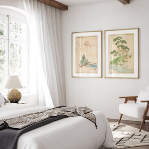 May include: Two framed Japanese-style prints of landscapes with trees and water. The prints are in gold frames and hang on a white wall.