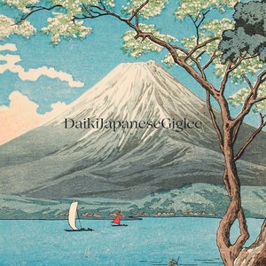 Op de afbeelding: Een schilderachtige prent met de berg Fuji met een besneeuwde top, tegen een blauwe lucht met wolken. Een boom omlijst de sc&egrave;ne en zeilboten stippelen het blauwe water af. De tekst "DaikiJapaneseGiglee" is op de afbeelding gedrukt.
