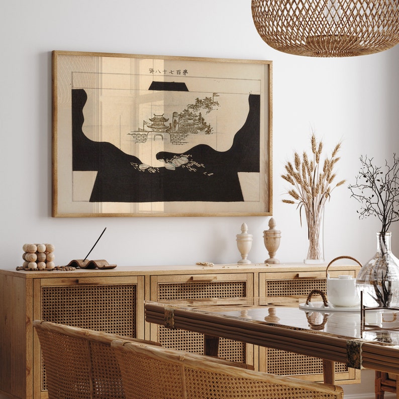 May include: A black and white print of a Japanese landscape with the text "外八大石碑" in the upper right corner. The print is framed and hanging on a white wall above a wooden cabinet with woven cane doors.