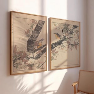 May include: Two framed prints of Japanese woodblock prints depicting birds perched on branches of cherry blossom trees. The prints are in shades of brown, white, and yellow.