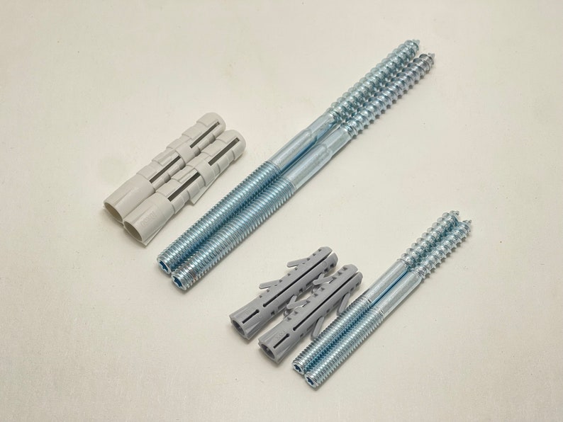 May include: An assortment of construction hardware, including several silver-colored screws and gray plastic wall anchors. The screws are long and threaded, designed for secure fastening. The anchors are cylindrical and ribbed for insertion into walls.
